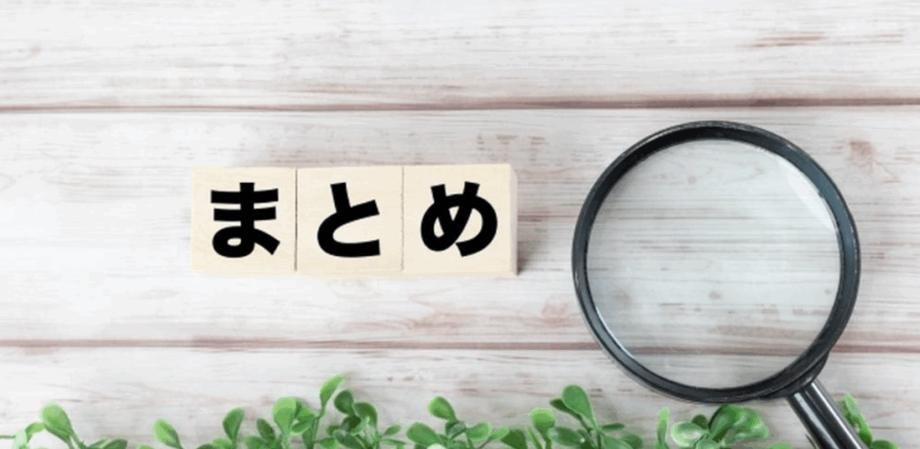 木目のテーブルに「まとめ」と書かれたブロックと虫眼鏡、植物の装飾。