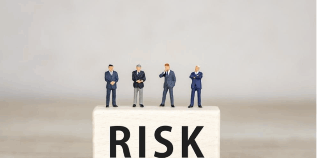 「RISK」の上に立つスーツ姿のビジネスフィギュア4体のイメージ